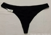A single pair of black women's thong panties with lace trim, laid flat on a light surface showing front and waistband details.