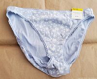 Front view of the light blue bikini panties with white snowflake pattern and lace trim. Shows the tag indicating size medium and brand.