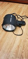 Black HP ProLight floodlight on wooden floor showing front reflective lens and attached power cord.