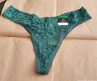 Front view of green lace thong underwear with tags attached.