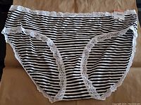 Front view of black and white striped Jenni hipster underwear with white lace trim and new tag attached.