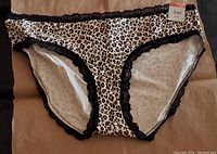 Front view of wild leopard print hipster panties with black lace trim, showing size tag 'Jenni' and new condition.
