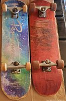 Top view showing one skateboard with a cosmic design and another with a red deck and visible scuffs.