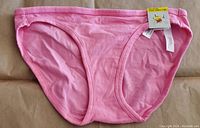 Front view of medium-sized pink bikini bottom with tag attached, showing solid color and elastic seams.