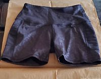 Black women's stretchy yoga shorts laid flat showing front side with side pockets.