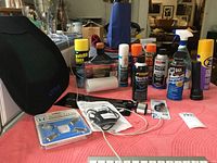 Various automotive and cleaning products including seat cushion, cans of spray, small parts on pink cloth