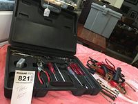 Black hard plastic tool case opened showing screwdrivers, hammer, ratchet wrench, sockets and other hand tools.
