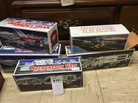Lot of five boxed Hess trucks with winter holiday-themed packaging displayed on table.