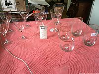 Set of eight large wine glasses, two water tumblers, and two barrel glasses arranged on a pink textured tablecloth