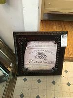 Front view of the 19 inch square metal framed wall art showing embossed wide metal frame and French label insert.