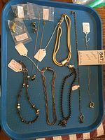 Image showing multiple necklaces and pairs of earrings laid out on a blue tray.