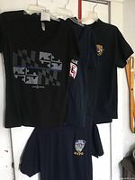 Four police-themed and MedEvac-themed tees hanging on hangers showing front designs and logos.