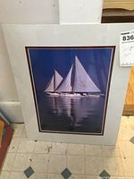 Photo shows the 16x20 photograph of a sailboat with double white mat, shrink wrapped, with a MaxSold label indicating it is a sailboat photo priced at $40.00