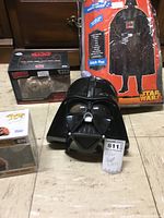 Darth Vader costume in packaging, Darth Vader mask, Funko Pop box, and Star Wars collectible vehicle box.