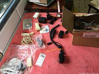 Mixed telephone accessories and power supplies on red surface with plastic bags and box