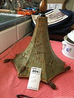 Full view of the green painted wood wall shelf with decorative bird motifs and pinecone-shaped finials at the corners, showing shape and top finial knob.