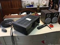 Yamaha RX-V383 AV receiver with Phillips box speakers and Samsung DVD player on table with two remotes.