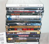 Stack of 16 rock and pop music DVDs showing spine titles including Coldplay Live 2003, AC/DC Let There Be Rock, Michael Jackson Live in Bucharest, Pink Floyd London 1966/1967, Metallica S&M, U2 Rattle and Hum, Radiohead The Astoria London, Foo Fighters Highways & Holidays.