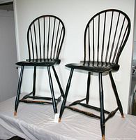 Photo showing the two black distressed Windsor style bar stools side by side from front angle.