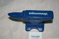Blue metal Benchmark anvil, top angled view showing logo and shape.
