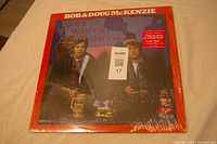 Front cover of Bob & Doug McKenzie 'Great White North' album in shrink wrap with red background and two men seated with drinks under map of Canada.