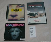 Front view of 3 Madonna items: MDNA Music 2000 CD, Truth or Dare DVD, The Confessions Tour DVD.
