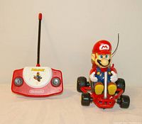 Photo of red Nintendo Mario Kart remote controller and Mario kart car with antenna attached.