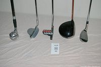 All golf clubs and ball retriever arranged side-by-side showing heads facing camera.