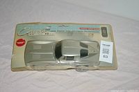 Front view of collectible Corvette telephone in clear plastic packaging displaying silver car design and branding.
