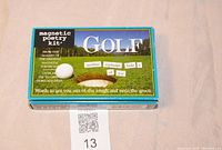 Photo of the front of the golf magnetic poetry kit box showing the brand, theme, and sample phrase 'another eighteen hole's of joy'.