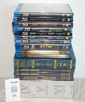Stacked view of Blu-ray and DVD cases of Star Wars, Lord of the Rings, Harry Potter and Hobbit films showing the titles and series.