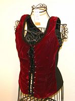 Front view of vintage burgundy bustier corset showing velvet fabric and lace-up front closure, displayed on decorative wire dress form.