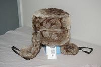 Full view of the XL Wind River faux fur winter hat showing its ear flaps and straps in a brown/beige faux fur material.