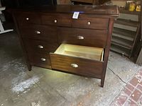 Full view of dresser showing dark wood finish, metal handles, and open bottom drawer revealing light wood interior.