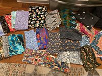 Multiple quilting cotton fabric pieces with various colorful patterns spread out on floor.