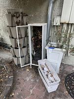Photo showing Gardenstalk 5-tier planter tower, Ikea terrarium cabinet with glass door containing dried plants, tall white planter, and two white window planter boxes stacked.