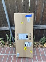 Tall rectangular cardboard box with shipping and handling labels, marked 'HEAVY'.