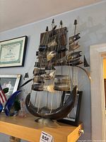 Sailboat horn sculpture placed on a shelf with visible string rigging and multiple horn sails.