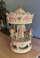 Front view of the detailed carousel music box showing horses and floral patterns.