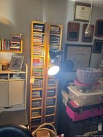 Photo showing all three tall, slim wooden CD shelves filled with CDs in an office space alongside other furniture and items.