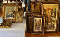Six framed artworks arranged on floor and storage bin