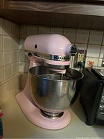 Front view of pastel pink stand mixer with bowl on countertop