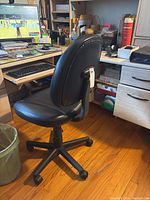 Back angle of the black faux leather office chair showing height adjustment and overall structure.