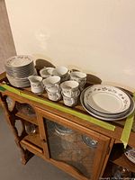 Overall view of the set showing bowls, cups, saucers, plates, creamer, and sugar bowl arranged on a wooden furniture piece.