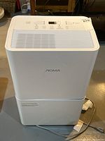 Front view of white Noma dehumidifier showing overall condition and branding on housing.