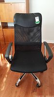 Front view of black office desk chair with mesh back, padded seat, and five caster wheels.
