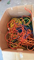 Box filled with tangled heavy duty outdoor extension cords in orange, yellow, green, and blue colors.