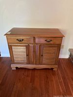 Front view of bottom wooden hutch showing two drawers and double doors with brass and wooden knobs.