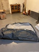 Inflatable air bed deflated and spread open on basement floor. Shows overall size and material of the bed.