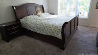 Full view of king size wooden sleigh bed with bedding in place showing bed frame and mattress
